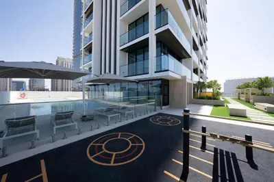 a building with a pool and some chairs and umbrellas at Relax In Style 1br Haven In Binghatti Venus! in Dubai