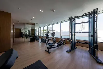 a gym with cardio equipment in a building with windows at Relax In Style 1br Haven In Binghatti Venus! in Dubai