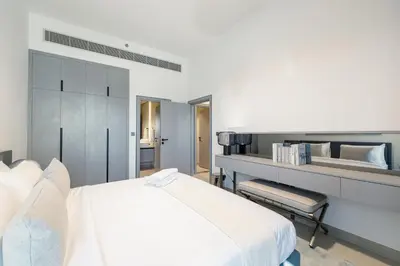a white bedroom with a bed and a chair at ALiving Elegant 1BR Apartment with Balcony I MAG960 in Dubai