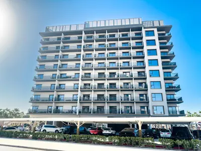a tall white building with cars parked in a parking lot at ALiving Elegant 1BR Apartment with Balcony I MAG960 in Dubai