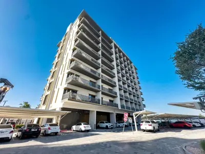 a tall building with cars parked in a parking lot at ALiving Elegant 1BR Apartment with Balcony I MAG960 in Dubai