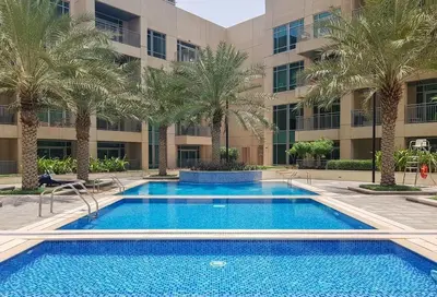 a swimming pool in front of a building with palm trees at Vibrant 2BR in Burj Views - Near Dubai Mall & Burj in Dubai