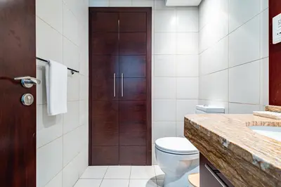 a bathroom with a toilet and a wooden door at Vibrant 2BR in Burj Views - Near Dubai Mall & Burj in Dubai