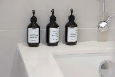 three bottles sitting on top of a bathroom sink at Luxury Canal Front with Burj Khalifa Skyline View in Dubai