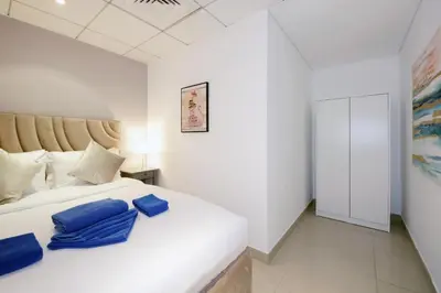 a bedroom with a white bed with blue pillows at Stylish 1BR plus study room with Queen bed in Dubai