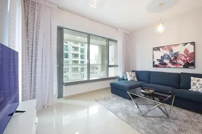 a living room with a blue couch and a window at Stylish 1BR plus study room with Queen bed in Dubai