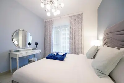 a bedroom with a large white bed and a mirror at Stylish 1BR plus study room with Queen bed in Dubai