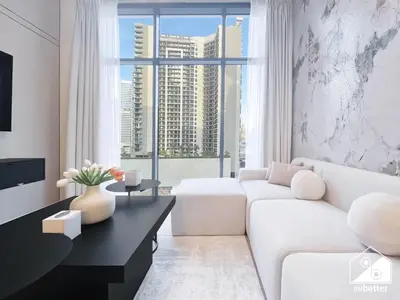 a living room with a white couch and a large window at Luxury 2BR in Merano Tower & Stunning Canal Views in Dubai