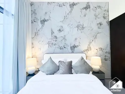 a bedroom with a white bed and a marble wall at Luxury 2BR in Merano Tower & Stunning Canal Views in Dubai