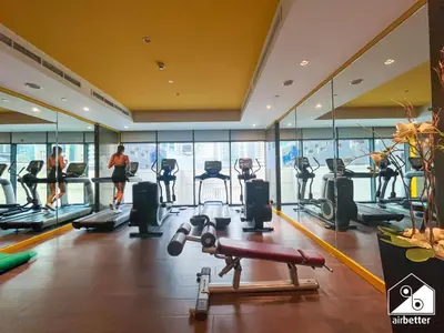 a gym with cardio equipment and people exercising in the background at Luxury 2BR in Merano Tower & Stunning Canal Views in Dubai