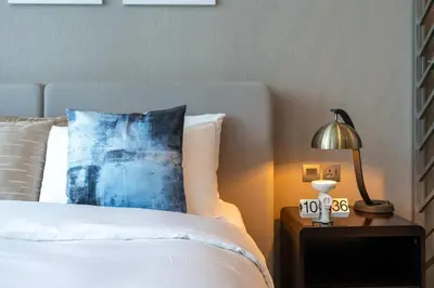 a bedroom with a bed with a blue pillow and a lamp at Luxury Canal-View Studio in Dubai