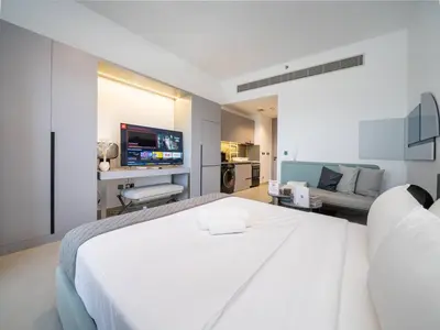 a white bedroom with a large bed and a couch at Contemporary Meydan Studio Escape in Dubai