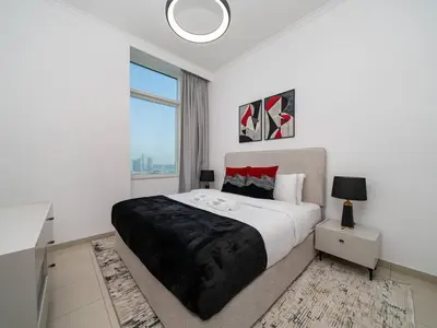 a white bedroom with a large bed and a window at Elegant 1-Bedroom Retreat with Marina Views in Dubai