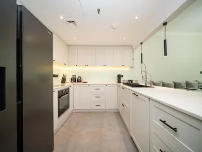 a kitchen with white cabinets and a stainless steel refrigerator at Luxurious 2 Bed Waterfront Living at Marina Quays in Dubai