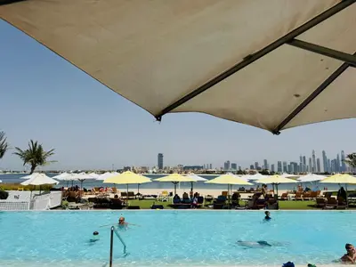 a swimming pool with people in the water and umbrellas at Best View Luxury 2BDR Palm Jumeirah, Beach & Pool in Dubai