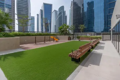 a park with benches and grass in a city at Perfect Location-For Work or Leisure in Dubai