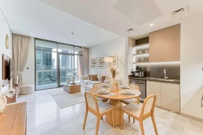 a kitchen and living room with a table and chairs at PVH - Lavish 1BR in Peninsula Five in Dubai