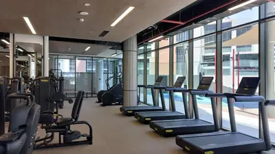 a gym with a row of treadmills and machines at PVH - Lavish 1BR in Peninsula Five in Dubai
