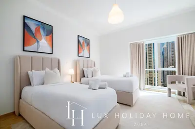 two beds in a white room with a window at LUX The Al Seef Marina Suite 2 in Dubai