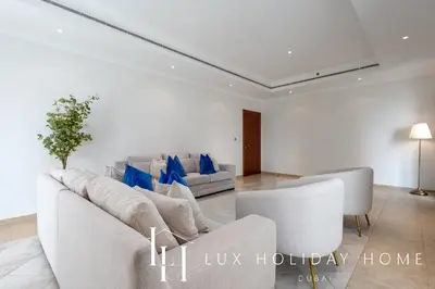a living room with a white couch and blue pillows at LUX The Al Seef Marina Suite 2 in Dubai