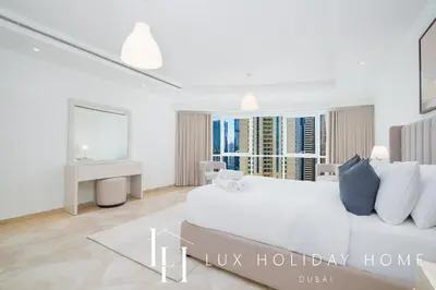 a white bedroom with a large bed and a desk at LUX The Al Seef Marina Suite 2 in Dubai