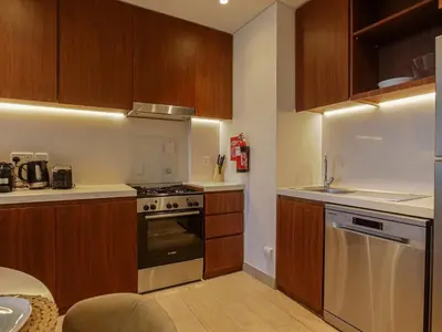 a kitchen with wooden cabinets and a stove top oven at HiGuests - Modern Escape in Jumeirah Bliss in Dubai