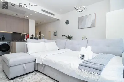 a white bedroom with a bed and a kitchen at Stylish 1BR in Peninsula Five Views & Pool in Dubai
