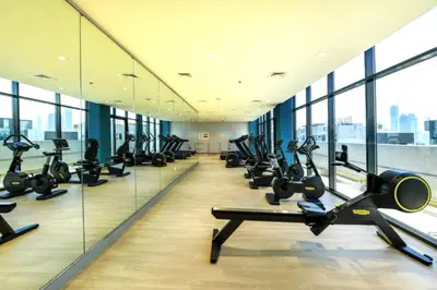 a gym with a row of treadmills and ellipticals at Studio with Pool and Community View, Near Soho Garden DXB and Meydan Golf Club, Azizi Riviera 43, Al Merkadh by Deluxe Holiday Homes in Dubai