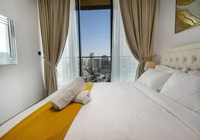 a bedroom with a large bed with two towels on it at Brand New Luxurious 1 BR with Garden, Gym, Pool and Open View in Dubai