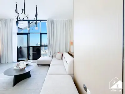 a living room with a white couch and a table at Cozy One-Bedroom in O2 Tower, JVC in Dubai