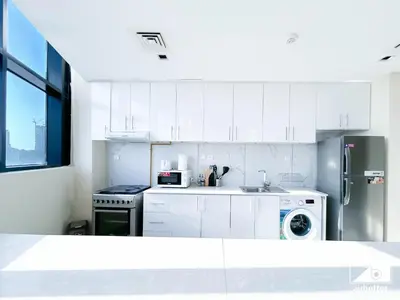 a kitchen with white cabinets and a stainless steel refrigerator at Cozy One-Bedroom in O2 Tower, JVC in Dubai