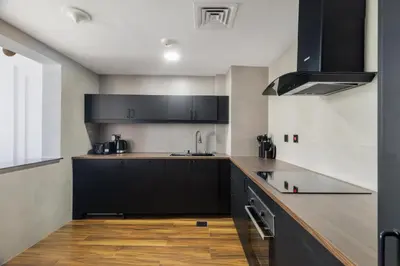 a kitchen with black cabinets and a wooden floor at Luxury Marina View with Jacuzzi, Arcade & Balcony in Dubai