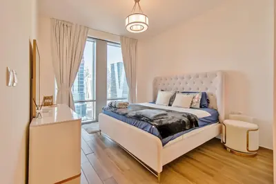 a white bedroom with a bed and a window at DreamShoma-1BR Stunning Canal View in Dubai