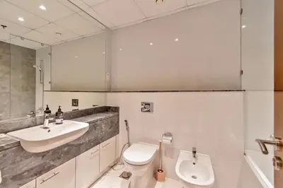 a white bathroom with a sink and a toilet at DreamShoma-1BR Stunning Canal View in Dubai
