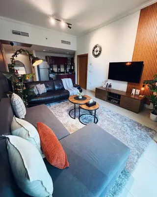 a living room with a couch and a tv at Dubai Marina Modern 1 Bedroom Apartment - steps to tram & Marina Walk in Dubai