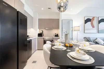 a kitchen and dining room with a black table and chairs at Mahogany 9 - 2BR 10PAX - Walk to Burj & Dubai Mall in Dubai