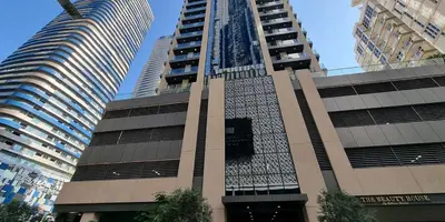 a building in a city with two tall buildings at Downtown Dunya Tower in Dubai