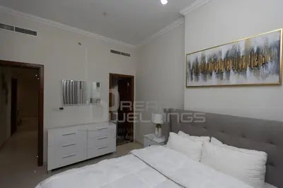 a white bedroom with a bed and a dresser at Downtown Dunya Tower in Dubai