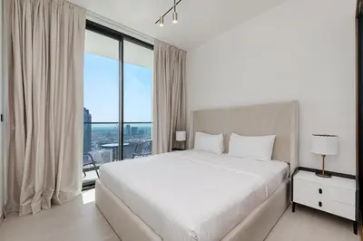 a bedroom with a white bed and a large window at Cozy 1BR apartment in Binghatti Venus JVC in Dubai