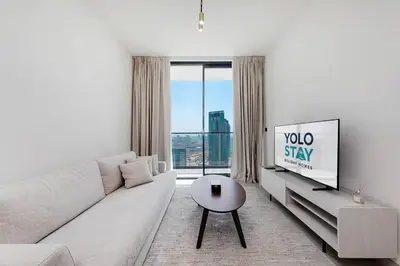 a white living room with a couch and a tv at Cozy 1BR apartment in Binghatti Venus JVC in Dubai