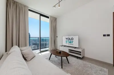 a living room with a couch and a large window at Cozy 1BR apartment in Binghatti Venus JVC in Dubai