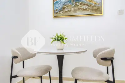 a table with two chairs and a potted plant on it at Bloomfields Luxurious Stu in Mulberry 1 Emirates in Dubai
