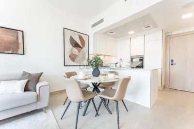 a kitchen and living room with a table and chairs at New 1 BR with 2 Balconies Near Circle Mall, Luma22 West Tower, JVC By Deluxe Holiday Homes in Dubai