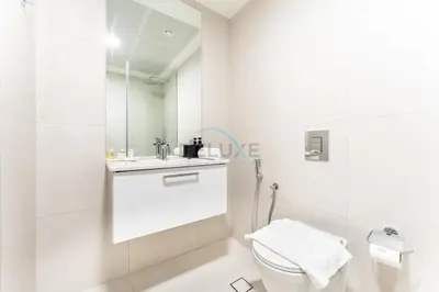 a white bathroom with a toilet and a sink at New 1 BR with 2 Balconies Near Circle Mall, Luma22 West Tower, JVC By Deluxe Holiday Homes in Dubai