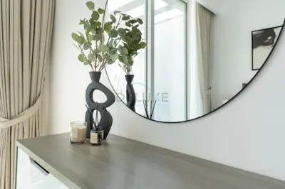 a table with a mirror and a vase with flowers at New 1 BR with 2 Balconies Near Circle Mall, Luma22 West Tower, JVC By Deluxe Holiday Homes in Dubai