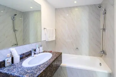 a bathroom with a sink and a tub and a mirror at Near Beach Luxurious 2-Bedroom in JBR in Dubai