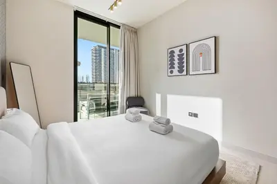 a white bedroom with a bed and a balcony at BLVD - Luxe Retreat - Stylish Stay with Full Privacy in Dubai