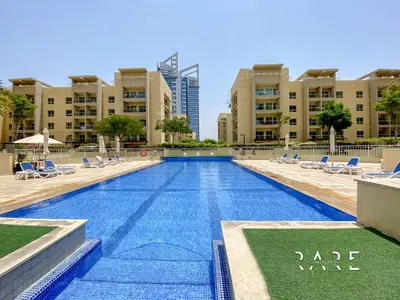 a large swimming pool with lounge chairs and buildings at Rare Holiday Homes - Near Metro Station - Greens - Al Arta - R215 in Dubai