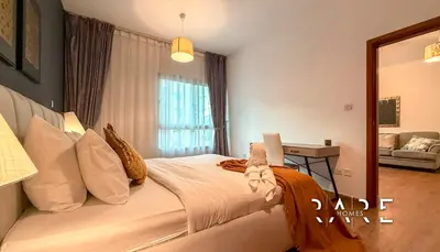 a bedroom with a bed with a desk and a window at Rare Holiday Homes - Near Metro Station - Greens - Al Arta - R215 in Dubai