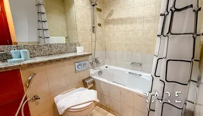 a bathroom with a toilet and a bath tub at Rare Holiday Homes - Near Metro Station - Greens - Al Arta - R215 in Dubai